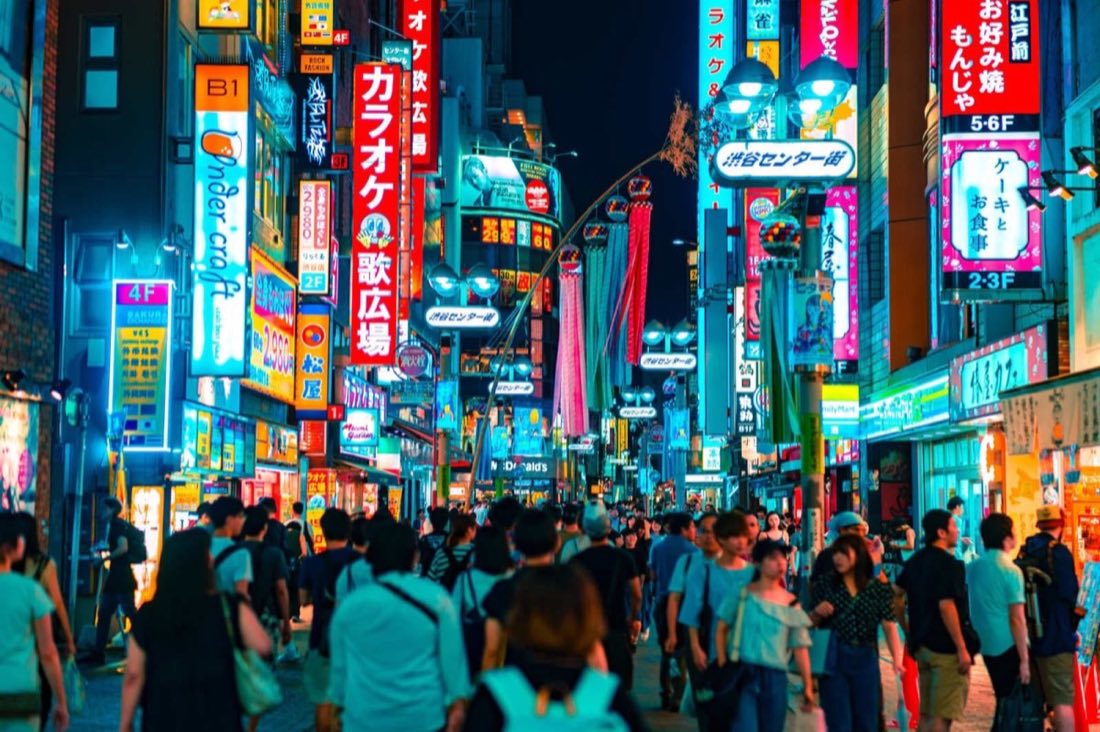 Neon-lit Shibuya shopping street crowded at night, Tokyo, Japan